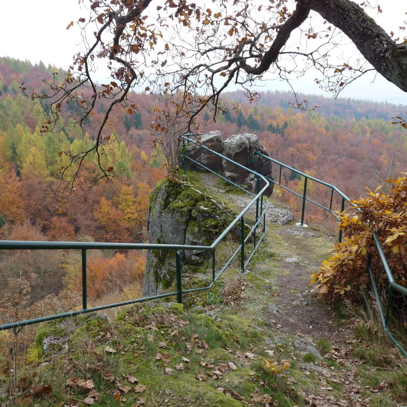 ein Geländer führt zu einem felsigen Aussichtpunkt im Herbst