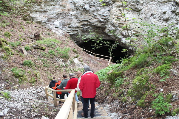 mehrere Personen steigen auf einer Treppe zu einer Grotte hinab