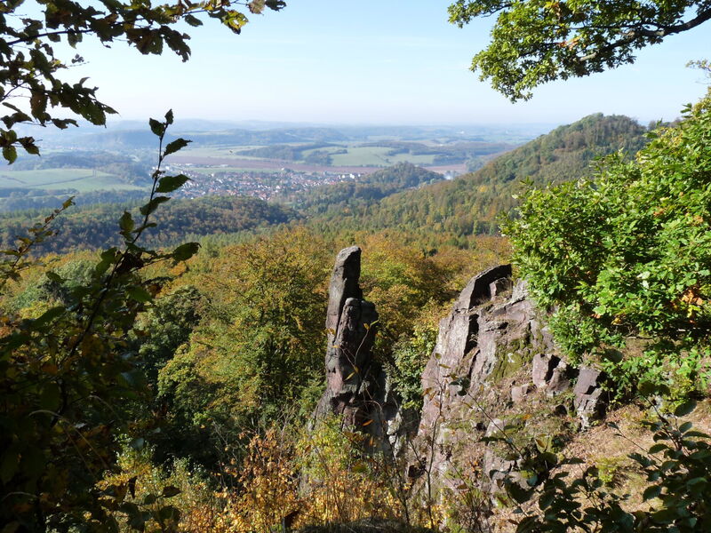 beeindruckende Aussicht im Herbst mit Felsformation, bewaldeten Bergkuppen und einer Ortslage in der Ferne